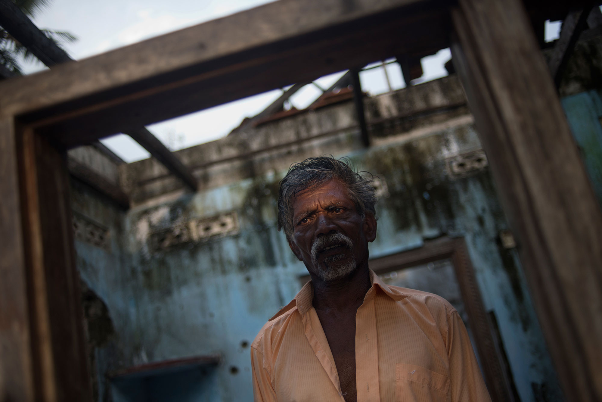 Anthony Fernando, a Tamil civilian, stands at the entrance of his house in the Mullaitivu district, which was badly damaged during the fighting. His wife and daughter were killed during the war. 