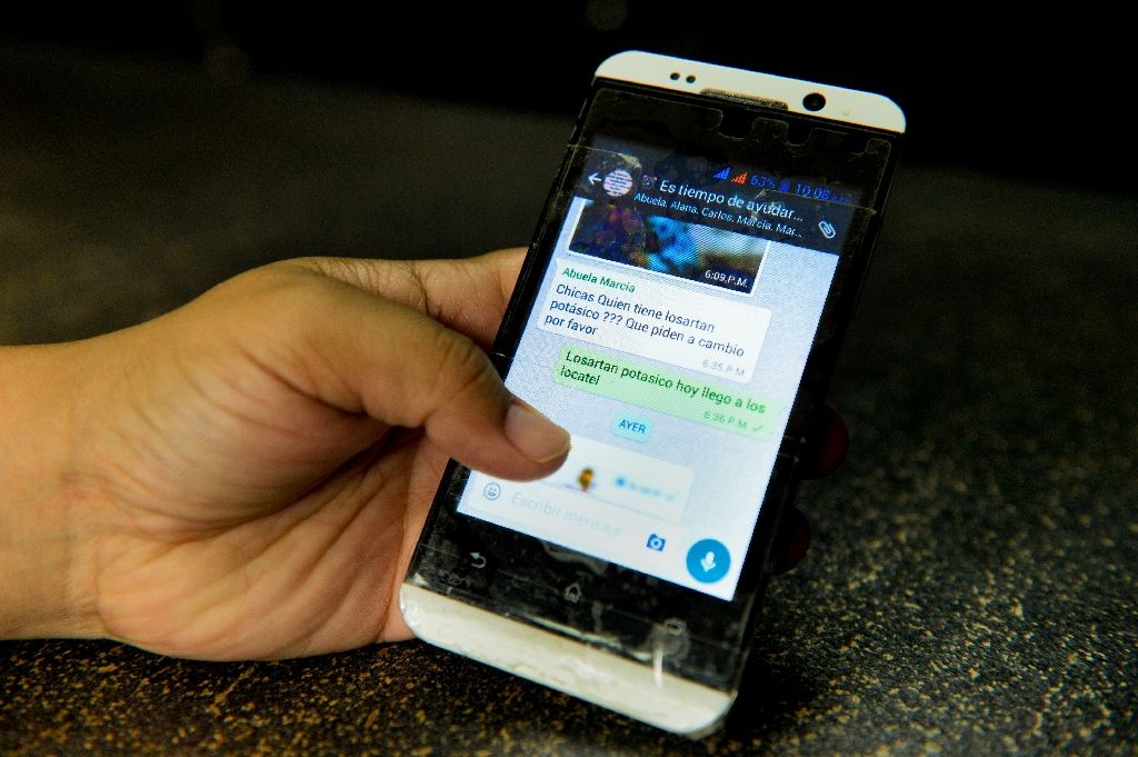 A person holds a mobile phone showing a Whatsapp group chat for the exchange of scarce products in Caracas on June 13, 2016