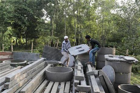 In this May 30, 2016 photo, Bangladeshi volunteers, working to spread awareness on sanitation, lift toilet seats in Bormi village, near Dhaka, Bangladesh. Bangladesh's success in sanitation, something so far unattained by India, came from a dogged campaign supported by 25 percent of the country's overall development budget. 