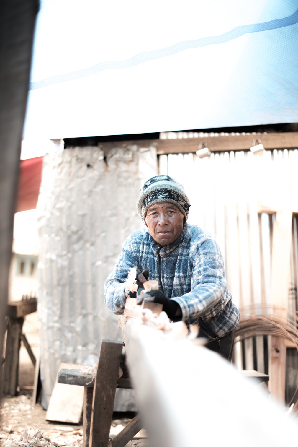 Lobsang, a carpenter who has travelled from Okhaldhunga, planes a wooden beam. He is one of many volunteers from other regions who have come to Langtang to help in reconstruction