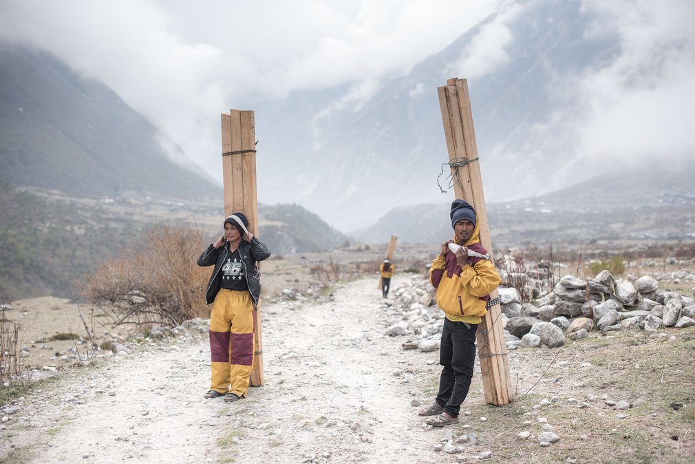 With few other forms of transport available â€“ the cost of helicopters is prohibitive â€“ teams involved in rebuilding the mountain villages have to walk for three days up the valley, hauling heavy loads of wood