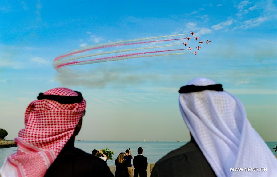 People watch the performance of the British Royal Air Force's Red Arrows flying display team near Kuwait tower in Kuwait City, Kuwait