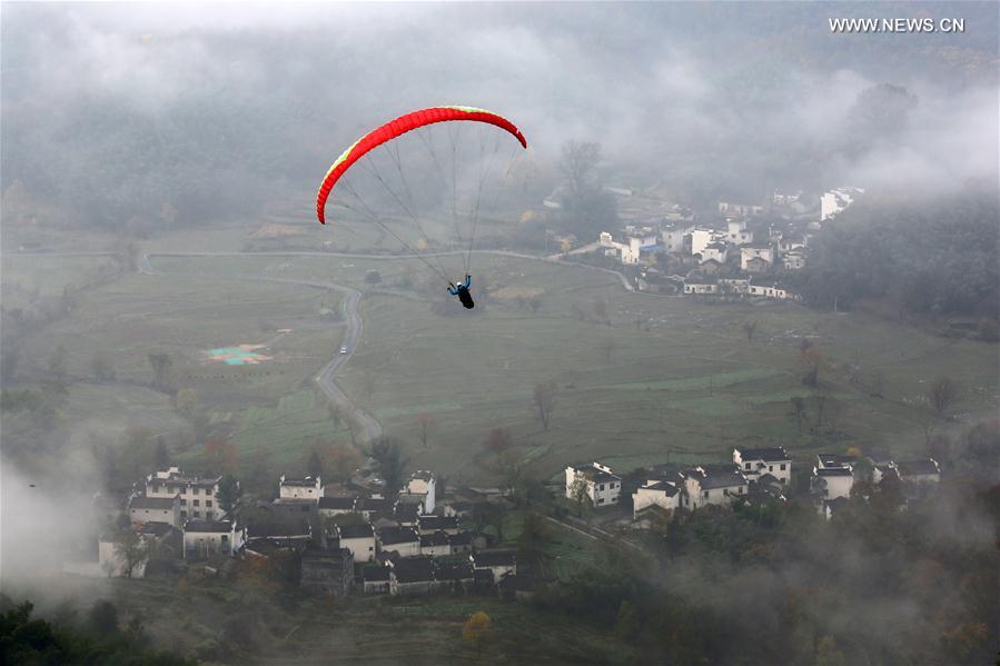 A person flies a glider over the Tachuan Village of Yixian County in Huangshan City, east China's Anhui Province, Nov. 19, 2016