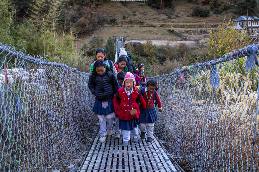 School children cross a suspension bridge over the Dhud Koshi River near Fakding village where the early warning system is installed.