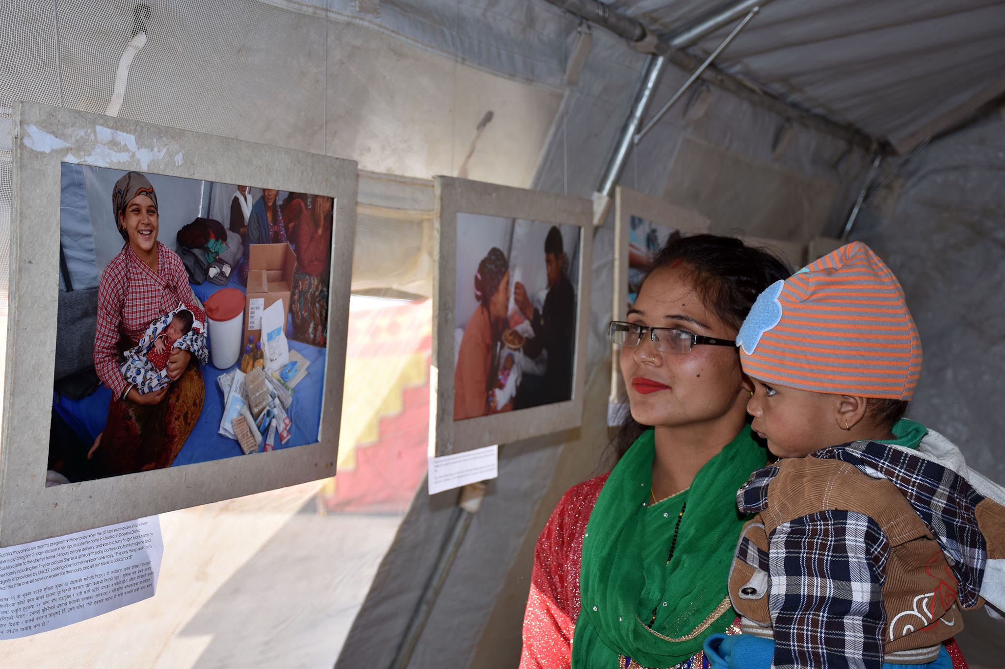 Sushila Phuyal and her 15-month-old son look at their photo displayed at UNICEF's 'Under the Tent' photo exhibition