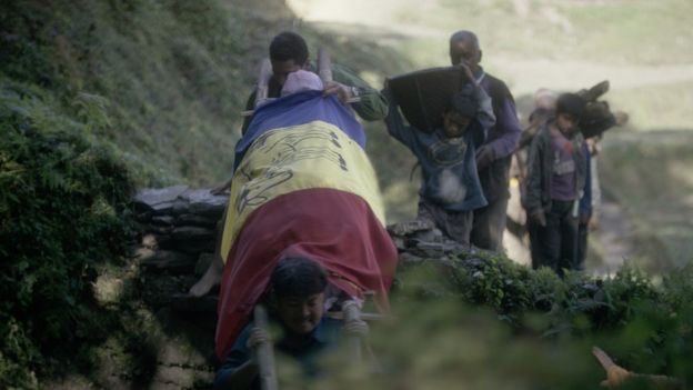 Chandra and Suraj carry the body of their father, draped in a royalist flag